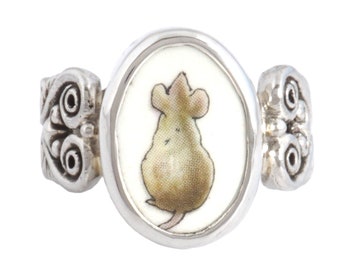 May include: A silver ring with a white oval cameo featuring a brown mouse with a long tail. The ring has ornate silver detailing on the sides.