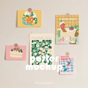 May include: A collection of five art prints, each featuring unique illustrations and designs. The prints are attached to a neutral wall with wooden clips. The prints include images of a cake, a strawberry in a bathtub, and floral patterns.