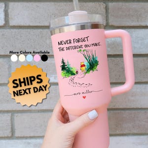 May include: A pink insulated tumbler with a handle and a clear lid. The tumbler features the text "NEVER FORGET THE DIFFERENCE YOU MAKE" and a Winnie the Pooh illustration. Additional colors are available.