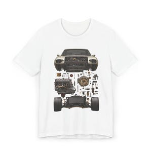 May include: White t-shirt featuring a detailed illustration of a car's components, including the engine, wheels, and body. The design showcases the car's parts in an exploded view, offering a unique and technical aesthetic.