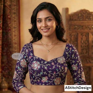 Puede incluir: Una blusa morada de manga larga con escote cuadrado y bordados florales. La blusa presenta una forma de V en el centro y está adornada con patrones florales coloridos. El texto "AStitchDesign" es visible en la esquina inferior derecha.