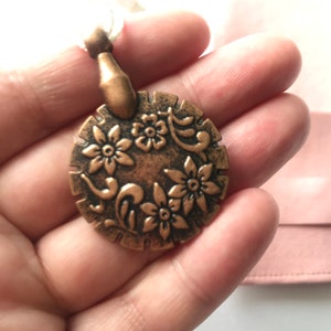 Bronze Thread Cutter with ivory tassel, in a  pink velour pouch.