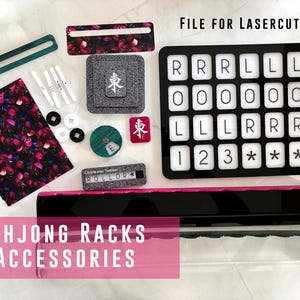 Puede incluir: Un conjunto de soportes y accesorios de Mahjong que incluye un tablero de rejilla negro con fichas blancas etiquetadas con R, L y números, una pieza de tela con estampado floral, fichas pequeñas blancas y negras, un rastreador Charleston y dos soportes acrílicos largos.