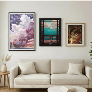 May include: Three framed art prints hang above a cream-colored sofa. The prints feature colorful illustrations, including a scene with a dragon and clouds, a coastal view, and a traditional Japanese scene. The room is decorated with a vase of dried flowers and a potted plant.