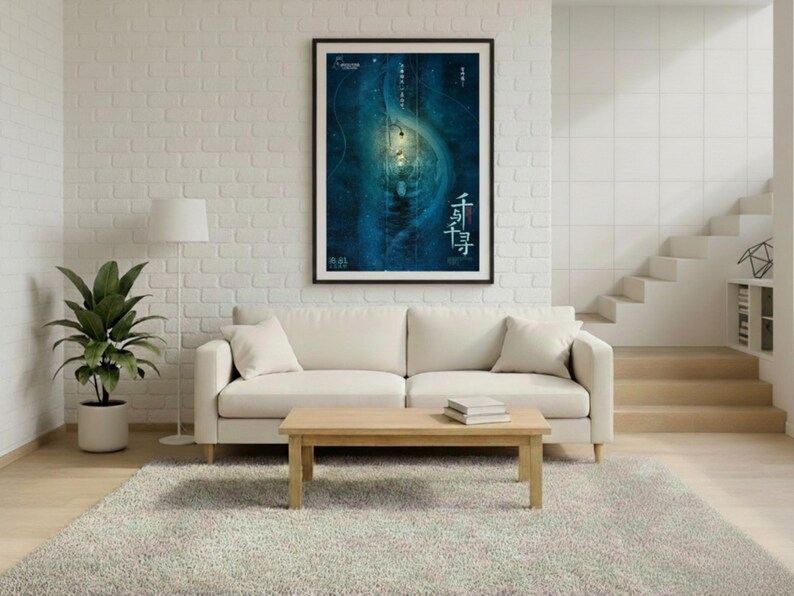 May include: A living room scene featuring a cream-colored sofa, a wooden coffee table, and a large framed poster with blue and white artwork. A potted plant and a floor lamp are also present. The room has a neutral color palette with a light gray rug.