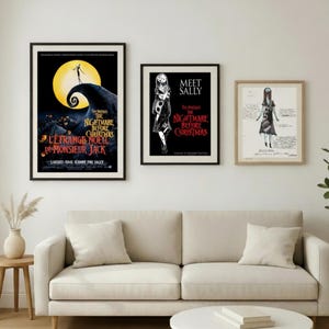 May include: Three framed posters featuring artwork from "The Nightmare Before Christmas" movie. The posters are displayed above a beige sofa. The first poster has the movie title in English and French. The second poster says "Meet Sally". The third poster is a sketch.