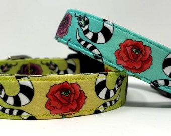 May include: Two dog collars with a black and white snake and rose pattern. One collar is turquoise with a red rose and the other is yellow with a red rose.