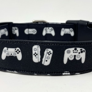 Puede incluir: Collar de perro negro con un patrón blanco de mandos de videojuegos.