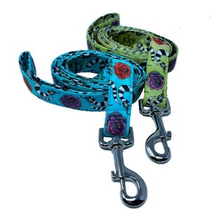 Puede incluir: Dos correas para perros con patrones florales y de serpiente. Las correas son turquesa y verde con clips plateados.