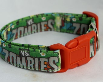 Puede incluir: Un collar de perro verde y gris con una hebilla naranja. El collar tiene el texto "VS. ZOMBIES" repetido.