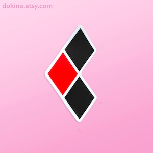 May include: A white-bordered sticker featuring a design of a red diamond shape and two black diamond shapes. The sticker has the text "dokino.etsy.com" at the top left and "@dokino" at the bottom right. The sticker is on a pink background.