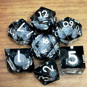 May include: A set of seven polyhedral dice for role-playing games. The dice are black with silver glitter and white numbering. Includes a D4, D6, D8, D10, D12, D20, and a percentile die.