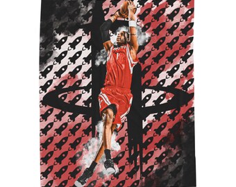 May include: A red and black blanket featuring a basketball player in action, mid-jump, with a basketball. The background has a pattern of black rockets on a red background. The Houston Rockets logo is also visible.