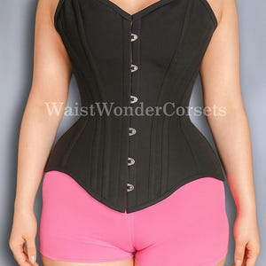 May include: A black corset with a sweetheart neckline and silver clasps. The corset is worn with pink shorts. The text "WaistWonderCorsets" is visible on the garment. The corset is a garment designed to shape the torso.