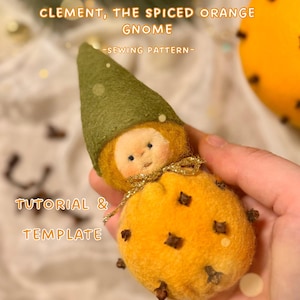 Könnte beinhalten: Eine handgefertigte Zwergenpuppe mit einem orangefarbenen Körper und einem grünen Hut. Die Puppe ist mit Nelken verziert und hat ein kleines Gesicht. Der Text auf dem Bild lautet "CLEMENT, THE SPICED ORANGE GNOME - SEWING PATTERN - TUTORIAL & TEMPLATE".