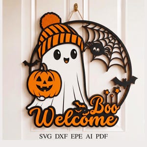 Puede incluir: Un colgante de pared circular de madera con un fantasma blanco que lleva un gorro de rayas naranja y sostiene una calabaza naranja. El diseño incluye una telaraña negra, murciélagos y el texto naranja "Welcome Boo". Abajo dice SVG DXF EPE AI PDF.
