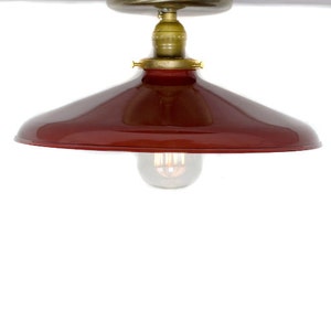 May include: A red metal ceiling light fixture with a brass finish and a clear glass light bulb.