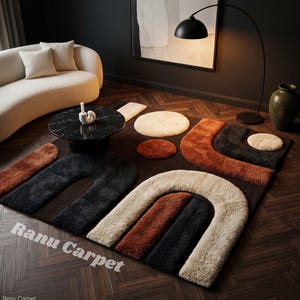 May include: A modern area rug with an abstract design in shades of brown, black, beige, and rust. The rug features curved and circular shapes, creating a geometric pattern. The text "Ranu Carpet" is printed on the rug.