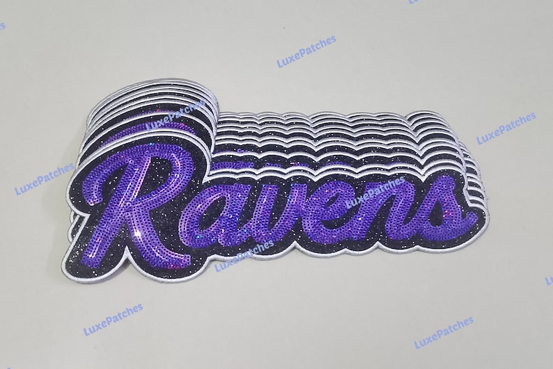 May include: A stack of embroidered patches featuring the word Ravens in a purple script font with a black glitter background and a white border. The patches are layered to create a three-dimensional effect, with the text LuxePatches visible.