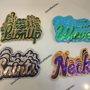 May include: Four sequined patches with text. "Lion Up" in green and gold, "Wave" in green and blue, "Saints" in gold and black, and "Neck" in purple and yellow. Each patch has a unique font and design.