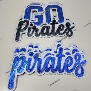 May include: Two embroidered patches with the words "GO Pirates" in blue, black, and white. The top patch has the word "GO" in a collegiate font. The bottom patch has the word "Pirates" in a cursive font.