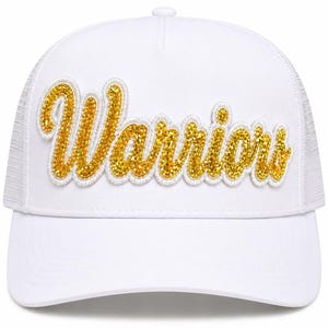 May include: A white trucker hat featuring the word Warriors in gold glitter script lettering across the front panel. The cap has a structured front, a curved brim, and a mesh back section. The gold text is outlined in white embroidery.