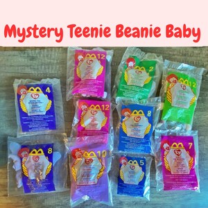May include: A collection of sealed, clear plastic packages of "Mystery Teenie Beanie Baby" toys. Each package has a colorful backing with the McDonald's logo, a number, and the Ty Beanie Baby logo. The text "Mystery Teenie Beanie Baby" is at the top.