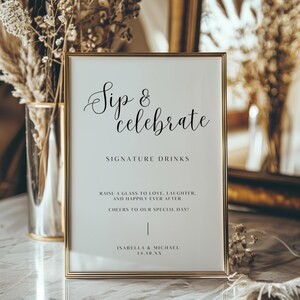 May include: A framed sign with the words "Sip & Celebrate" in elegant script. Below, it reads "Signature Drinks" and includes a celebratory message. The sign is in a gold frame, perfect for a wedding or special event.