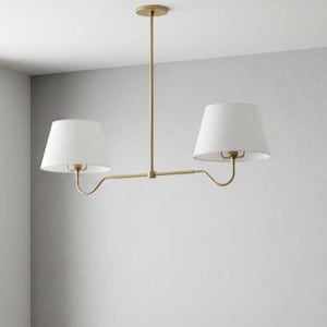 May include: A gold-coloured, two-light pendant light fitting with white lampshades. The fitting has a central vertical rod attached to the ceiling, with a horizontal bar extending to hold the two lamps. The lampshades are conical.