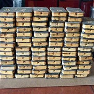 Op de afbeelding: Een stapel vintage houten letterpress drukblokken. Elk blok is rechthoekig met een donkergrijze bovenkant en een vergeeld houten lichaam. De letters A, B, C, D, E, F, G en H zijn zichtbaar op de bovenste blokken. De blokken zijn gestapeld op een bruin oppervlak.