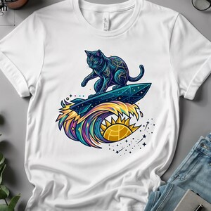 May include: White t-shirt with a black cat surfing on a surfboard above a colourful wave with a sun and stars design. The cat has geometric patterns. The shirt has the text "Nine Lives Dream".