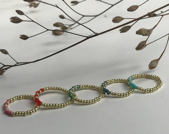 Anelli impilabili elastici realizzati con perline Miyuki dorate e inserti colorati.