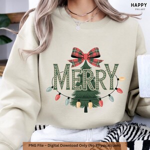 Op de afbeelding: Beige sweatshirt met een kerstboomontwerp. Het woord "MERRY" is groen, met een geruite strik erboven. Een slinger van kleurrijke lampjes omringt de boom. De tekst "PNG File - Digital Download Only (No Physical Item)" staat onderaan.