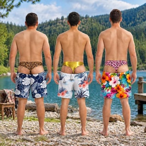 Può includere: Tre costumi da bagno indossati con perizomi abbinati. Il modello a sinistra è blu navy con motivi a foglie bianche. Il modello centrale è bianco con una stampa tropicale e un perizoma dorato. Il modello a destra presenta una vivace stampa floreale con un perizoma leopardato rosa.