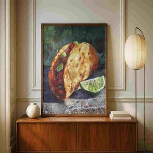 May include: A framed oil painting of a taco with a lime wedge. The taco has a golden-brown shell and is filled with red and green ingredients. The lime wedge is bright green. The painting is set against a dark green and gray background.