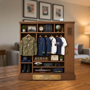 May include: A wooden display cabinet featuring miniature U.S. Navy uniforms, including a camouflage jacket, blue dress coats, and white shirts. The unit includes shelves with a globe, books, a ship model, a cap, boots, and a brass plaque reading CHRIST.