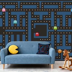 May include: A blue sofa with a Pac-Man themed wall mural. The mural features a maze design with colorful ghosts and Pac-Man. A yellow Pac-Man pillow and a black pillow with a pixelated design are on the sofa. A wooden rocking horse is on the floor.
