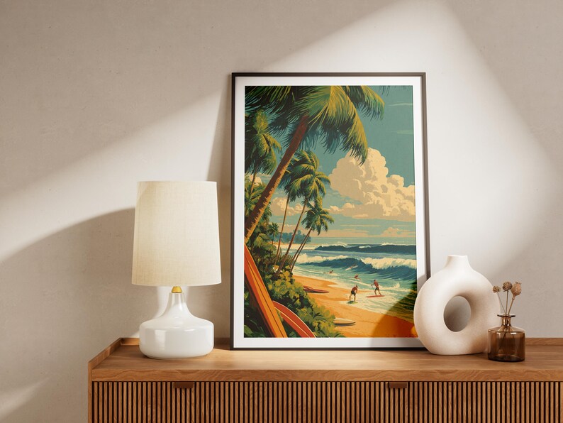 May include: Framed art print depicting a tropical beach scene with palm trees, surfers, and ocean waves. The artwork features a retro style with a color palette of blues, greens, and yellows. The print is displayed on a wooden cabinet with a lamp and vase.