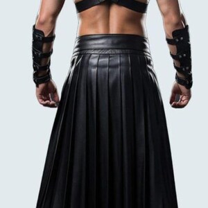 May include: Black leather kilt with matching shoulder and arm armor. The kilt is pleated and reaches the knees. The shoulder armor has studded accents. The arm armor is also black leather with studded details.