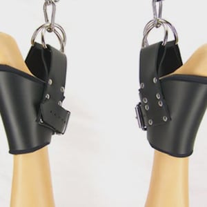 Peut inclure: Une paire de chevillières noires avec des ferrures métalliques argentées, comprenant des boucles, des rivets et des anneaux en D. Les manchettes sont doublées de rembourrage noir et suspendues par des chaînes métalliques pour les chevilles.