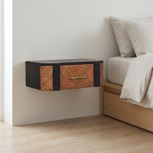 May include: A wall-mounted floating nightstand featuring a dark brown wooden frame and a central drawer front crafted from woven natural rattan. The drawer is accented with a slim, horizontal brass-toned metal handle centered on the front panel.