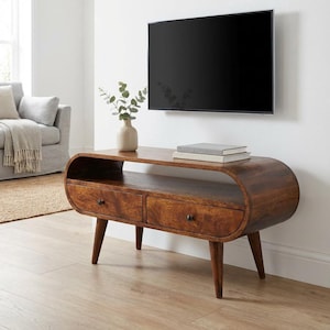 Könnte beinhalten: Ein TV-Schrank im Mid-Century-Modern-Stil aus dunklem Holz. Der Schrank hat zwei Schubladen, ein geschwungenes Design und konische Beine. Er ist etwa 122 cm lang und 46 cm hoch.