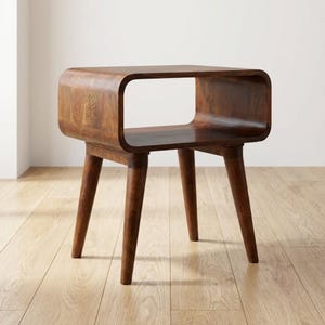 Può includere: Tavolino in legno marrone scuro in stile moderno di metà secolo. Il tavolo ha un piano rettangolare con un'apertura curva e tre gambe affusolate. Adatto per soggiorno o camera da letto. Dimensioni: circa 60 cm x 40 cm x 40 cm.
