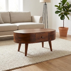May include: Oval wooden coffee table with a single drawer and four tapered legs. The table is a rich brown colour and sits on a cream rug. The table's length is approximately 120 cm.
