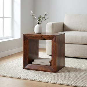 May include: A square, dark brown wooden side table with a hollow center and a thick frame. The table features a smooth, polished finish showing natural wood grain patterns. Inside the open compartment, two rectangular books are stacked neatly.