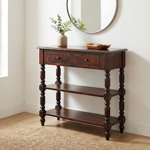 Peut inclure: Une console en bois brun foncé avec deux tiroirs et deux étagères. La table a des pieds tournés et est surmontée d'un vase de verdure et d'un bol en bois. Un miroir rond est accroché au mur derrière la table.