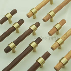 Könnte beinhalten: Eine Sammlung von Holzschrankgriffen mit messingfarbenen Akzenten. Die Griffe sind in verschiedenen Braun- und Naturholztönen erhältlich. Die Hardware ist für Möbel und Schränke konzipiert und bietet eine moderne Ästhetik.