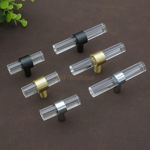 May include: A white ceramic mug with a black handle and the text "But First, Coffee" in a black, bold font. The mug is on a white surface.