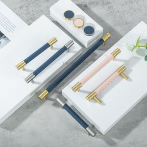 Puede incluir: Un conjunto de herrajes para armarios, que incluye tiradores en azul marino y rosa con detalles dorados y plateados. La imagen tambi&eacute;n muestra pomos redondos a juego en azul marino y rosa.