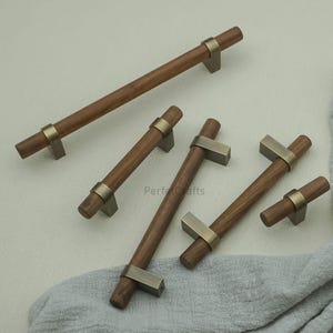 May include: A collection of wooden cabinet pulls with a dark brown finish and brushed metal accents. The pulls vary in size and are arranged on a neutral background. The text "Perfect Crafts" is visible on the image.